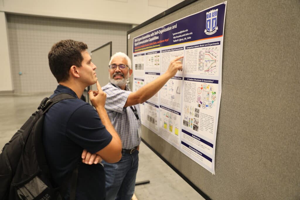 faculty researcher shares insights about a poster to an onlooker