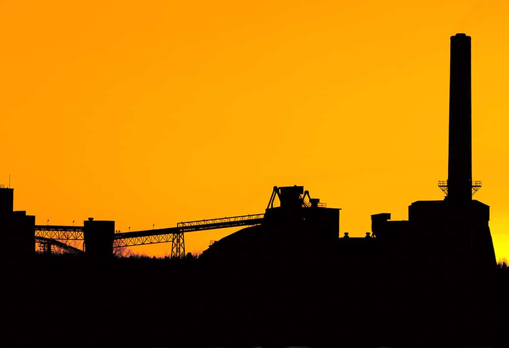 black silhouette of industry buildings on orange sky