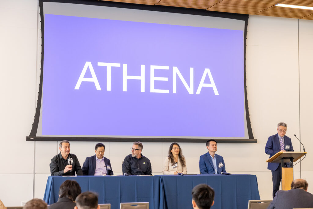 Five panels and a moderator speak on stage in front of a screen that says Athena