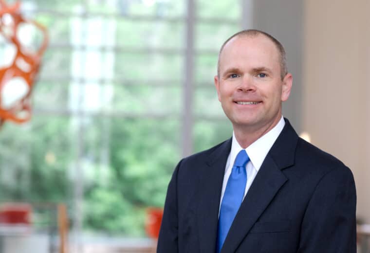 Pat Gunsch smiles in a blue tie and black suit jacket.