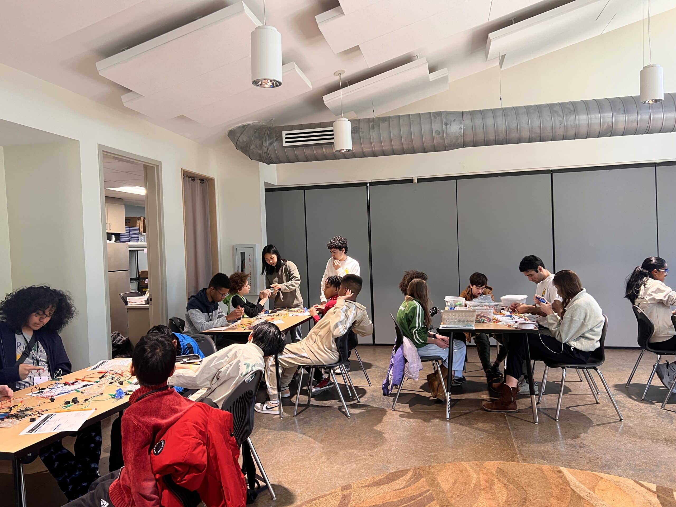 Students seated at tables in a workroom participating in program activities