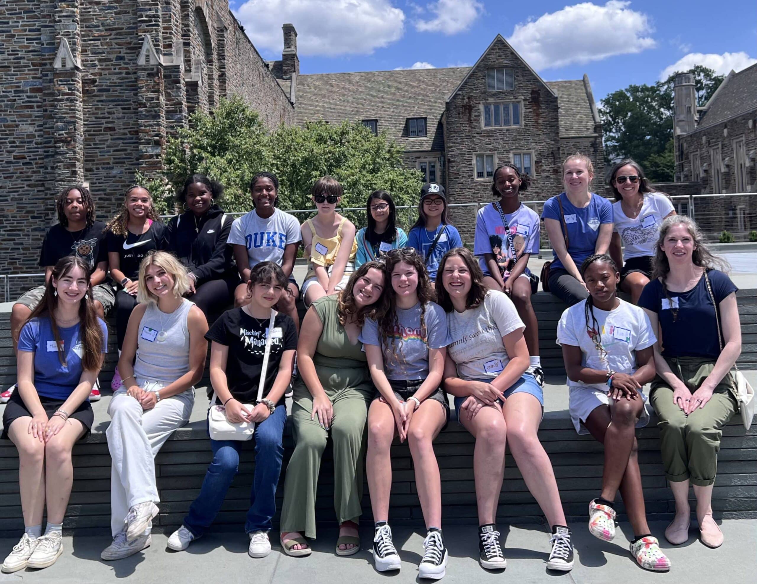Group photo of GEM student participants seated in two rows outside on the Bryan Center Plaza