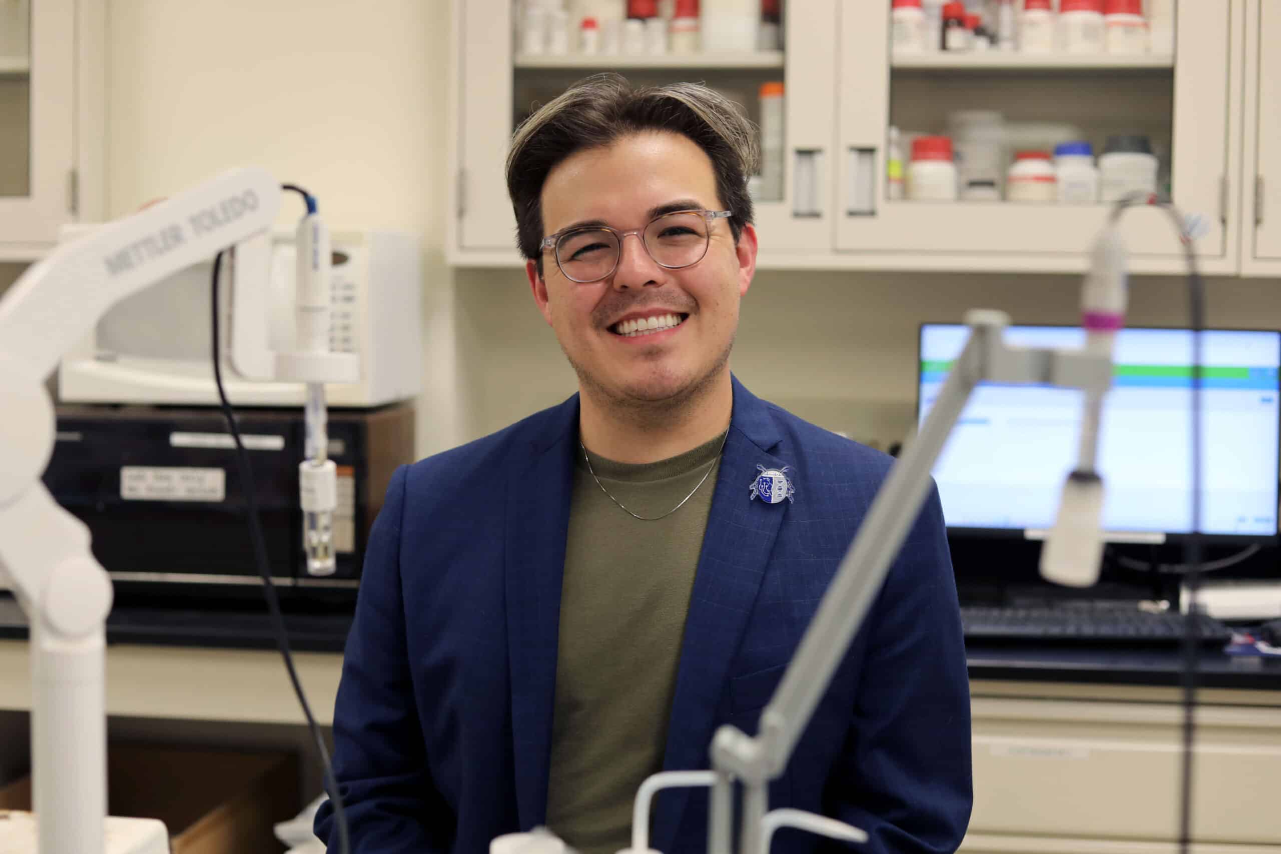 Cameron Kim poses in a blue blazer in a wet lab in the Teer basement