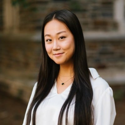 Yurong Huang smiles in front of a brick building on Duke University's campus.