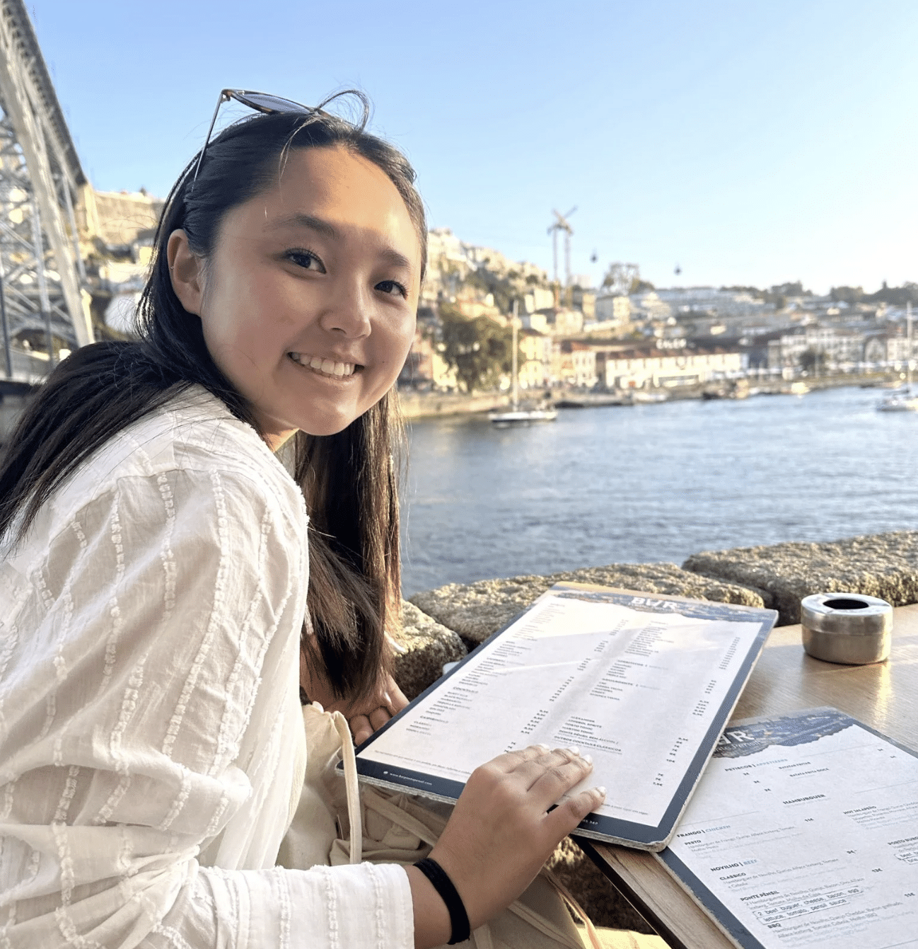 young woman sits with book near water and boats