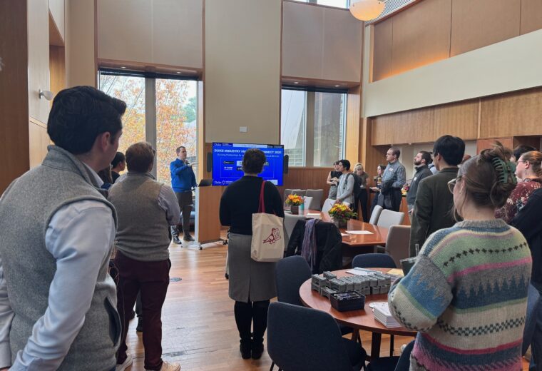 a group of people standing in a room watching a talk