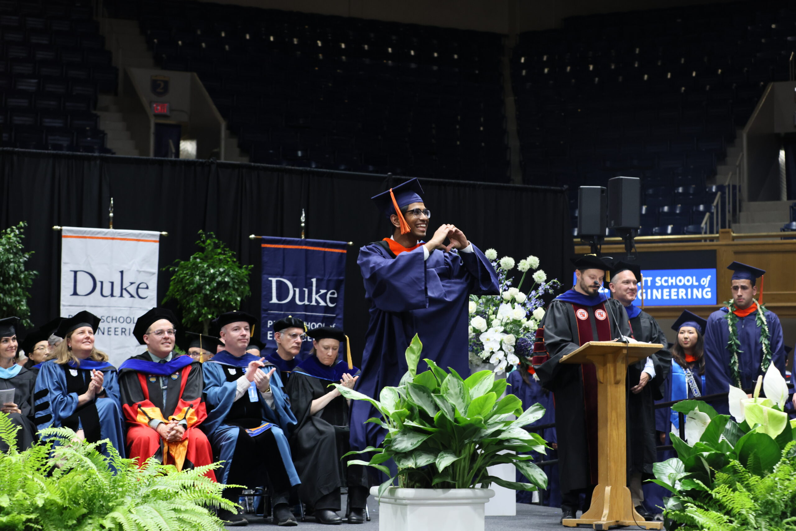 graduate makes heart shape with his hands as he crosses the stage during the undergraduate diploma ceremony in 2025